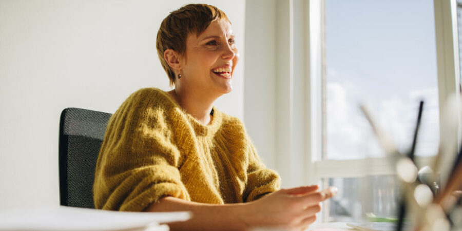 gluecklich-frau-schreibtisch_iStock-1324509582