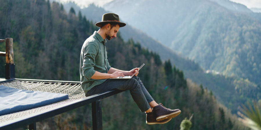 mann-reise-laptop-berge_iStock-1499876088