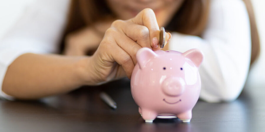 nahaufnahme-frau-muenze-sparschwein_iStock-1383886863